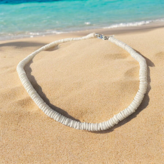 White shell necklace on a beach with the sea behind. Beach jewellery from Ben's Beach.