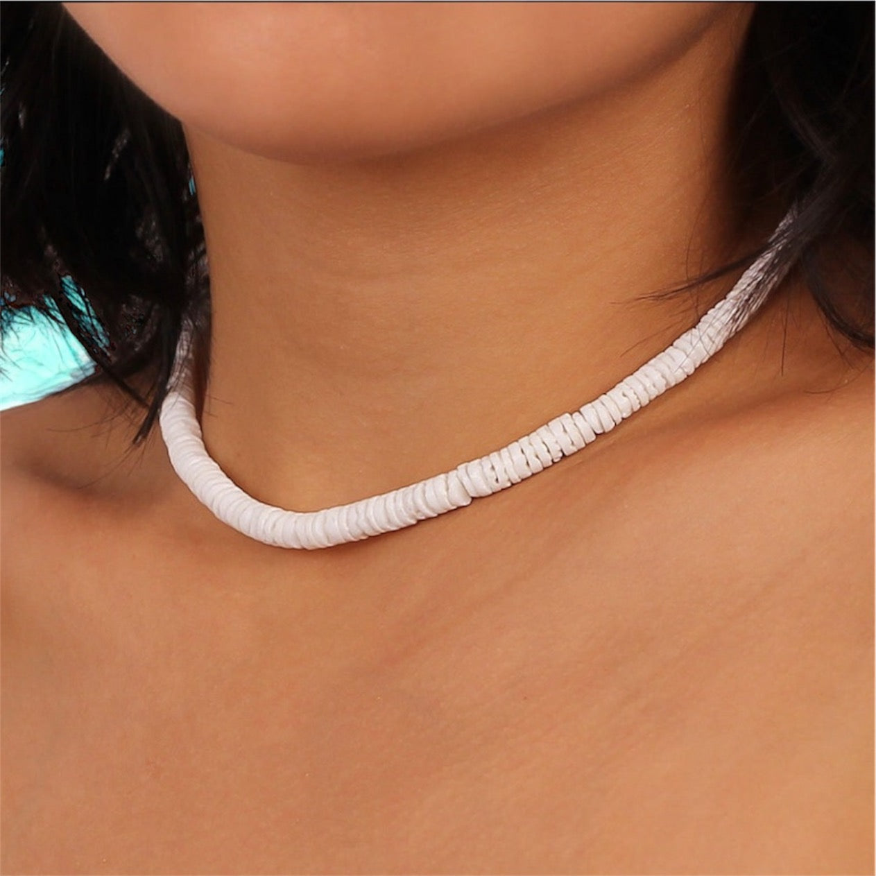Model wearing white shell necklace.