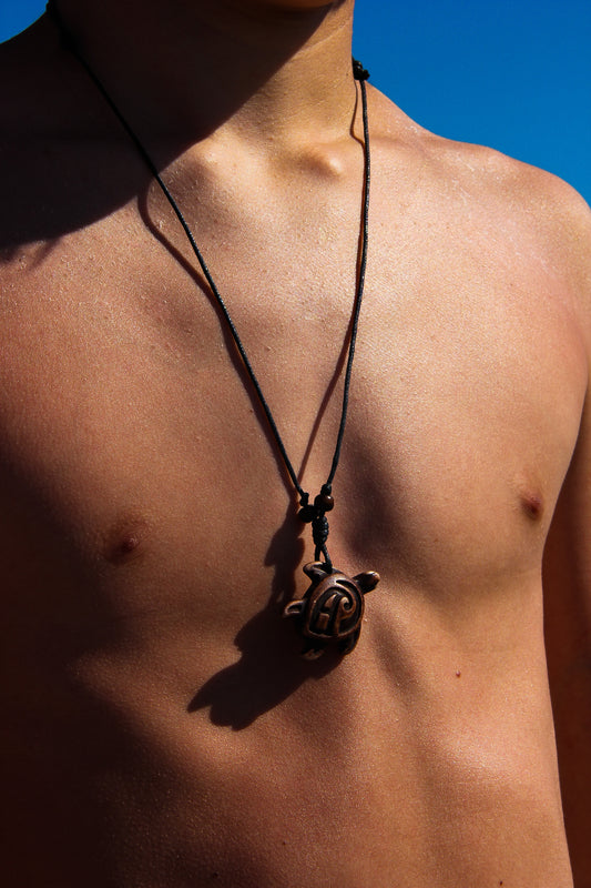 Male model wearing a black cord necklace with turtle pendant