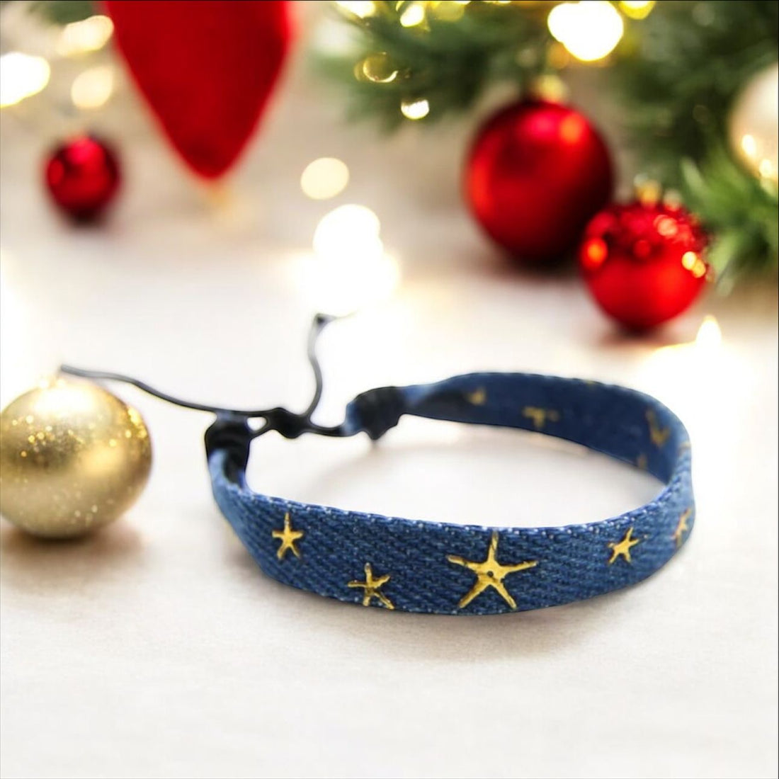 Denim bracelet with gold stars. Christmas decorations behind. 