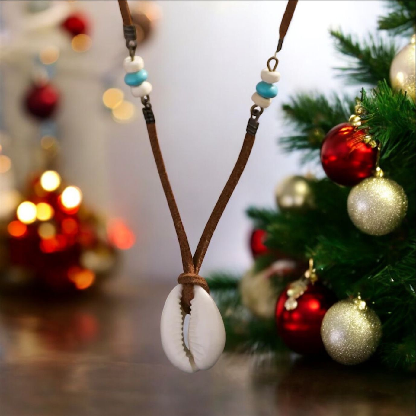 Leather necklace with white shell pendant and Christmas tree and decorations behind. 