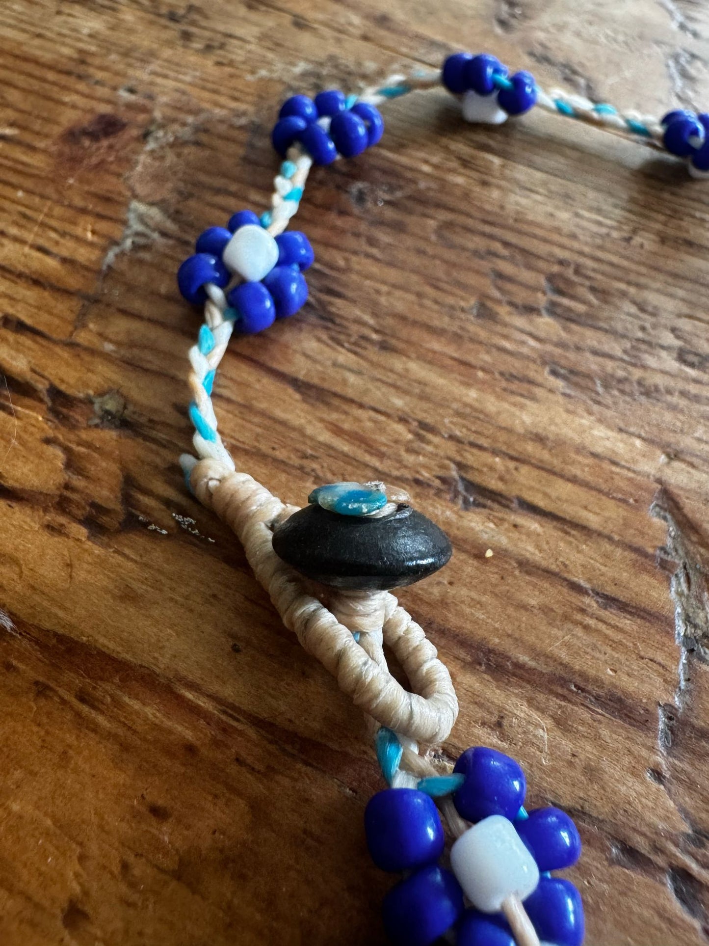 Close-up of brass button fastener on an anklet. 