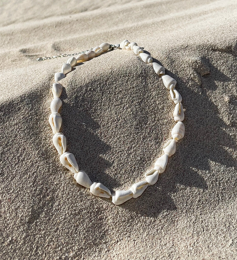 seashell necklace laying in the sand