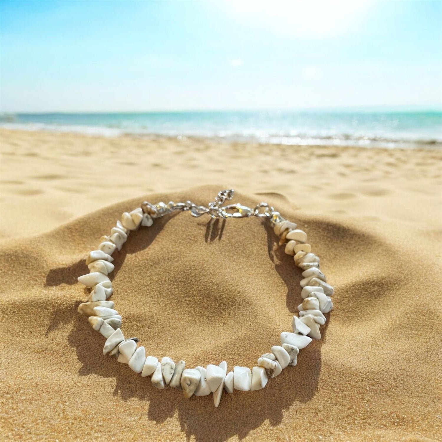 Bracelet made of stone chips on a beach with sea behind. 