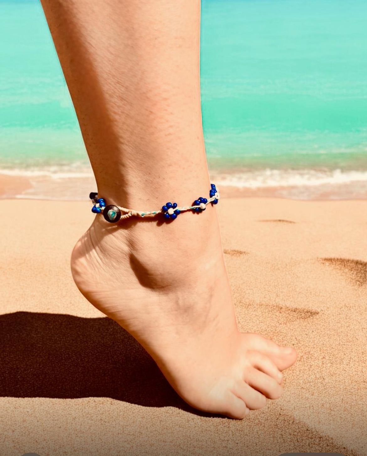 Woman wearing a flower anklet on a beach. 