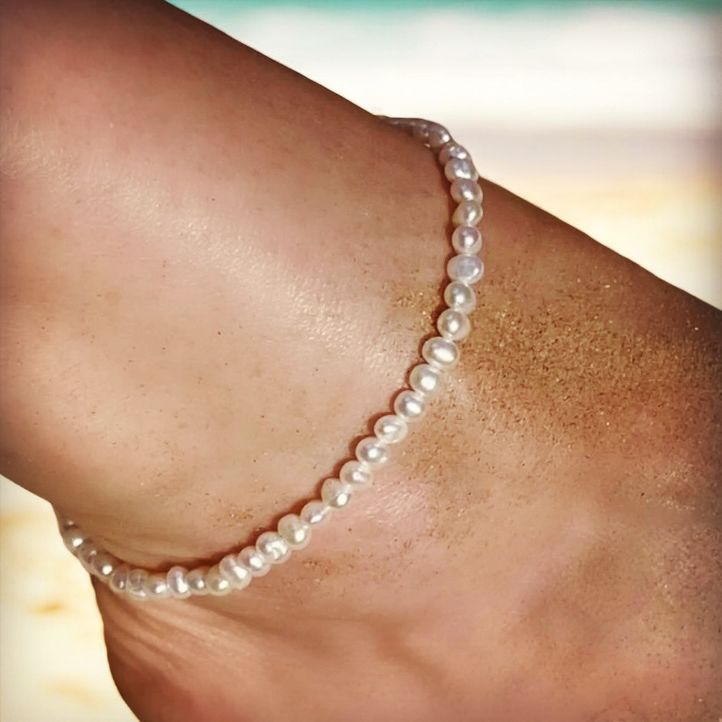 Model wearing a pearl anklet on the beach. 