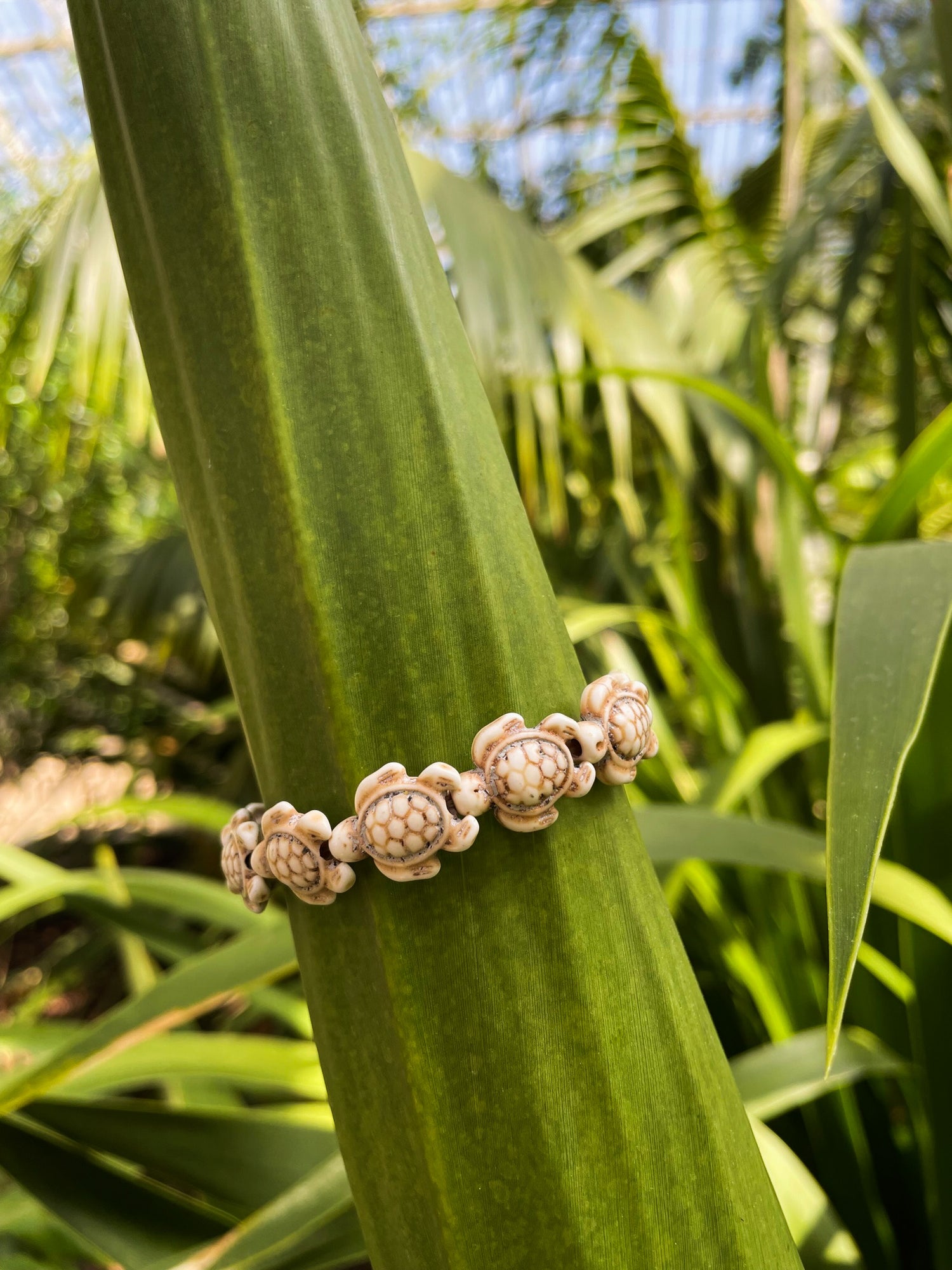 stone sea turtle bracelet displayed on a tropical plant
