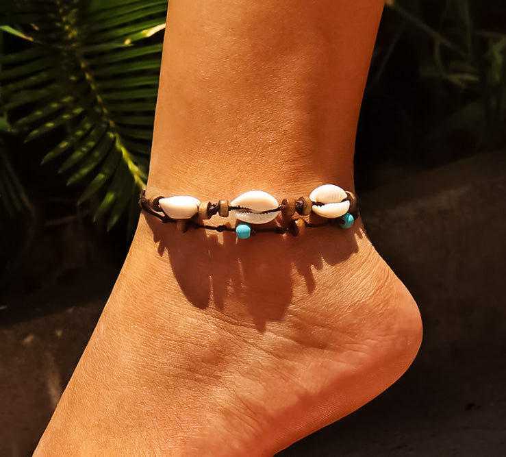 Model's foot with beach style anklet with shells and beads.