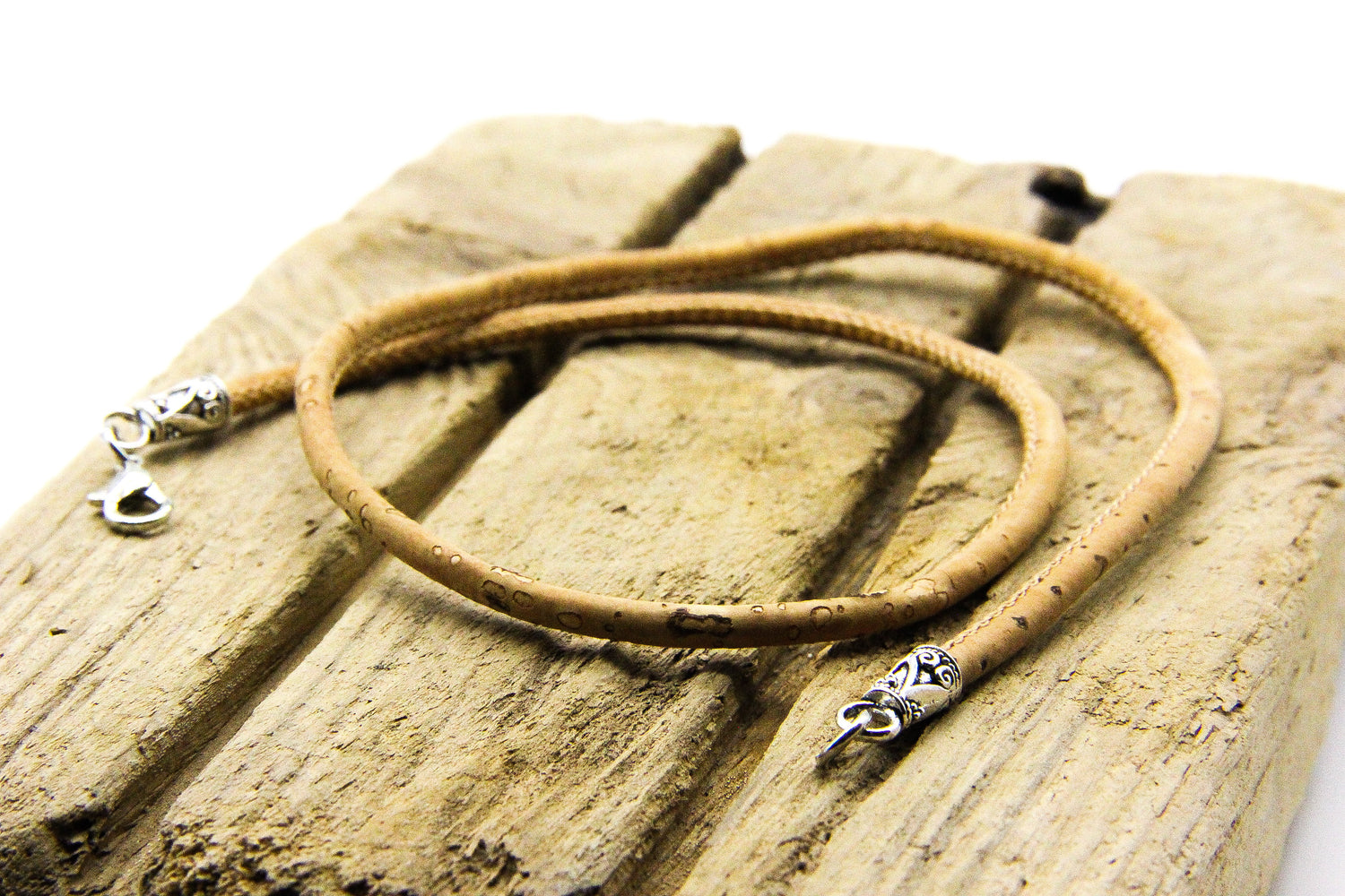 Cork choker with silver clasp displayed on a piece of wood.