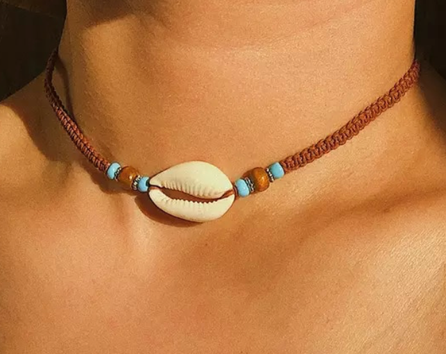 Model wearing brown choker with cowrie shell pendant and beads