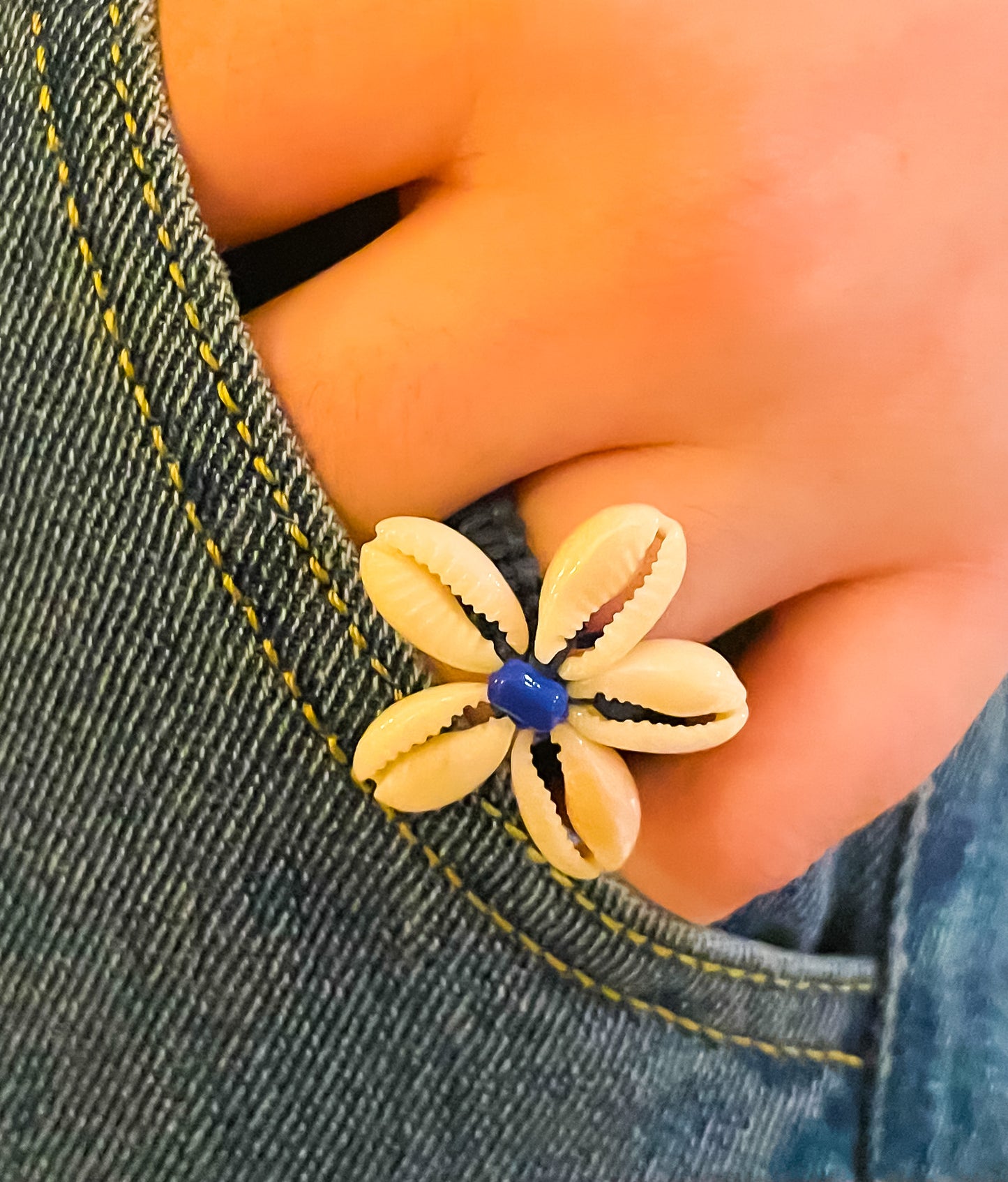 model wearing ring with cowrie shells in the shape of a flower