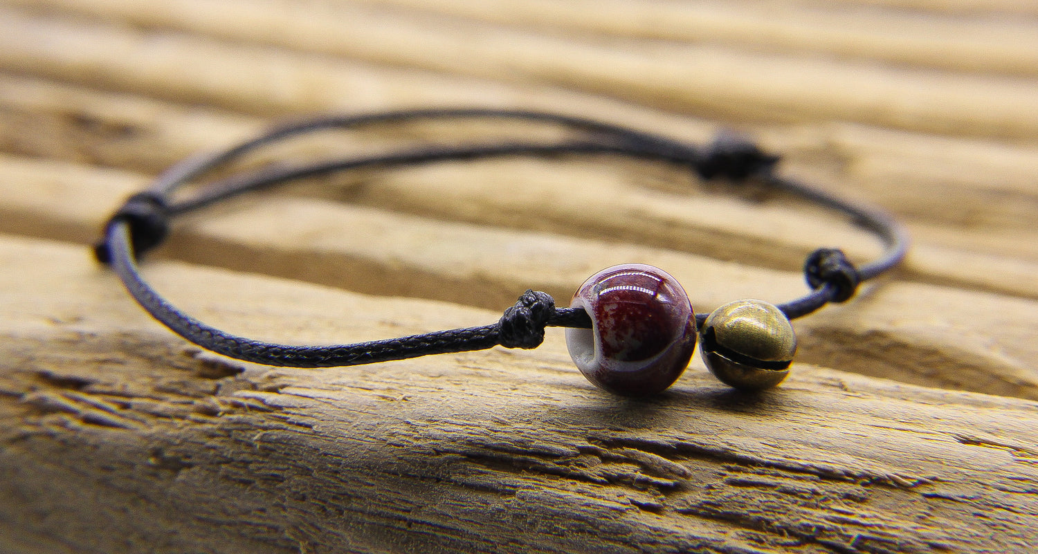 Black leather bracelet with tiny brass bell and maroon colour bead