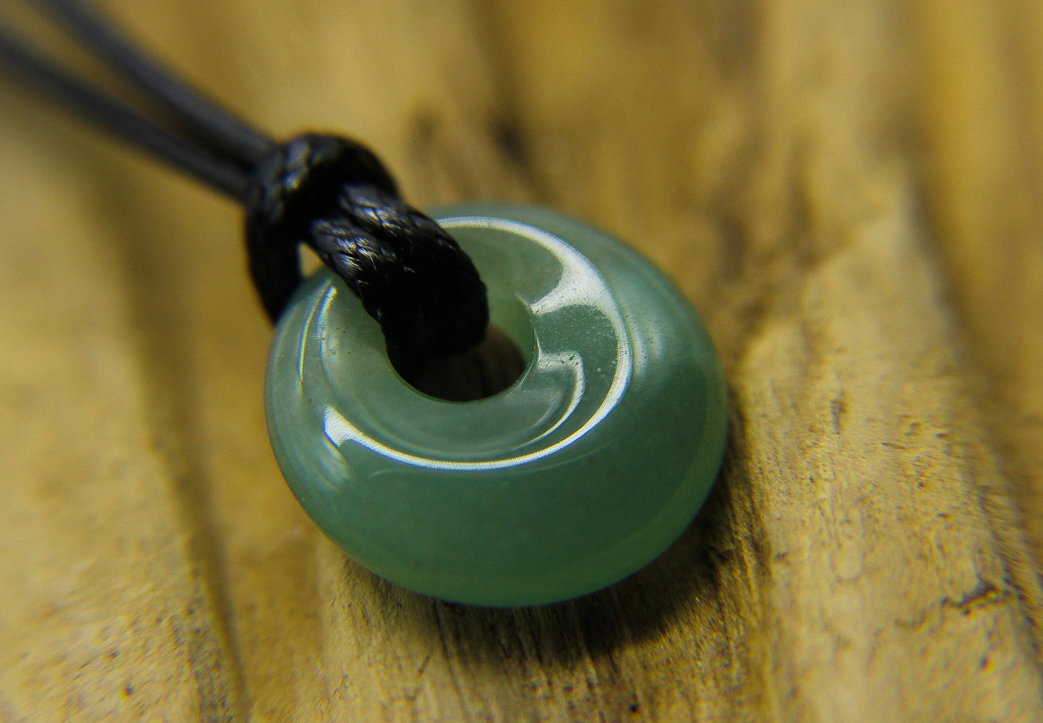 Green gemstone pendant on a black cord choker 