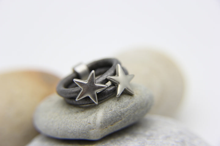 multi-strand grey ring with 2 silver stars on beach pebbles