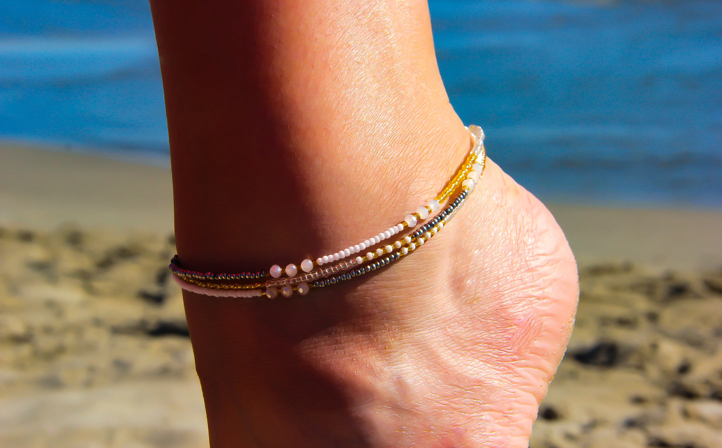 Seed Bead Anklet on model with sand and sea behind - Ben's Beach Jewellery UK