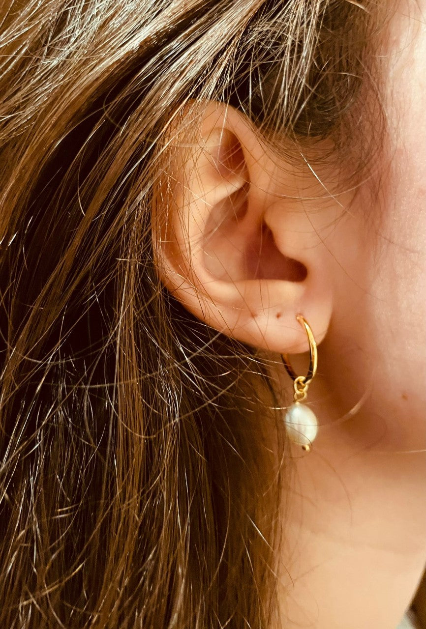 Model wearing gold hoop earrings with pearls