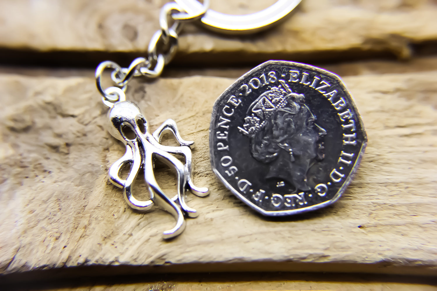Silver octopus pendant next to a fifty pence coin