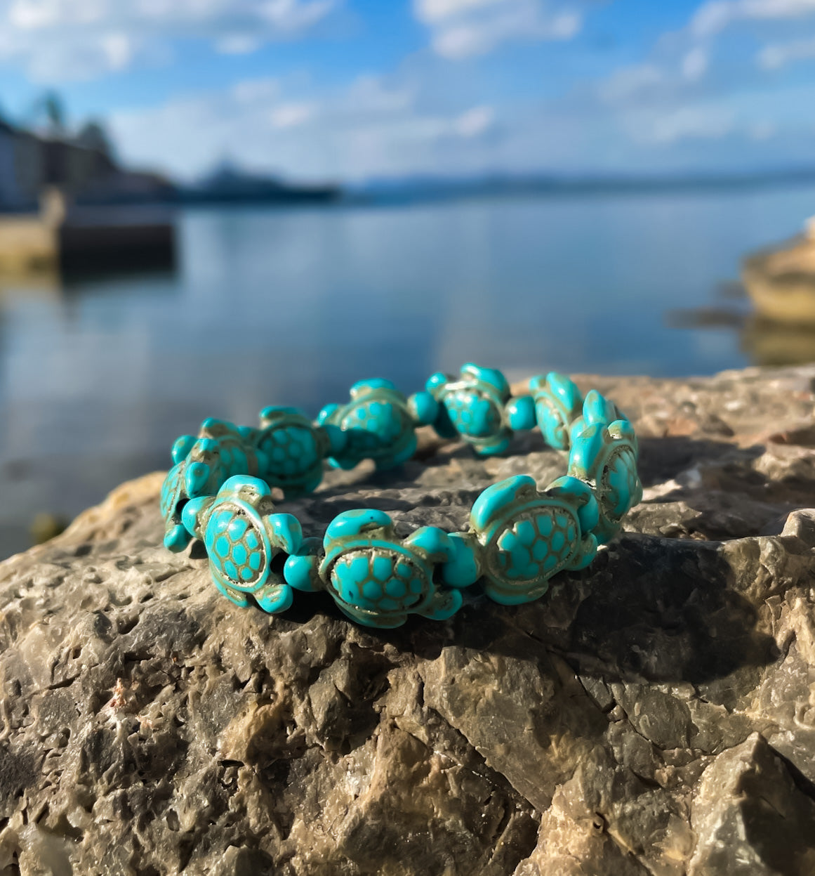 sea turtle stone bracelet on a rock with blue sea behind
