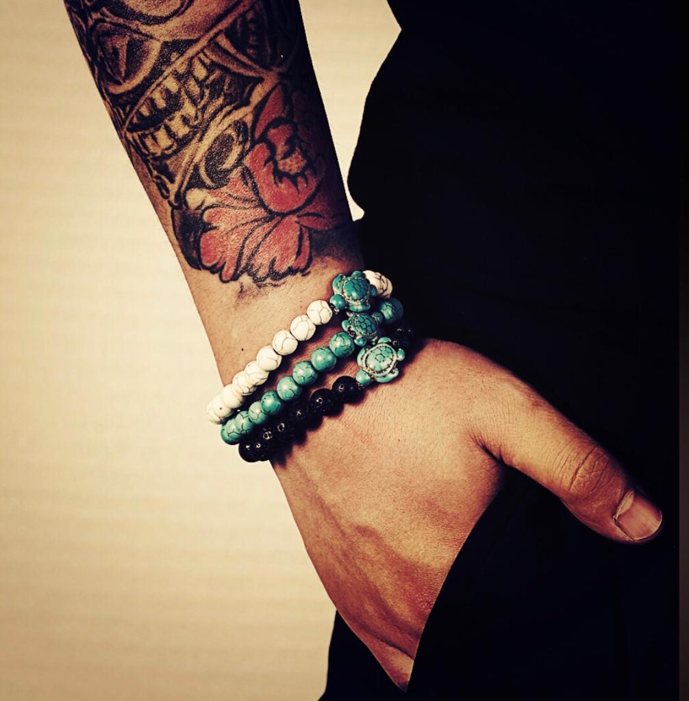 Male model's arm with tattoo weather 3 stone bracelets with sea turtle charms