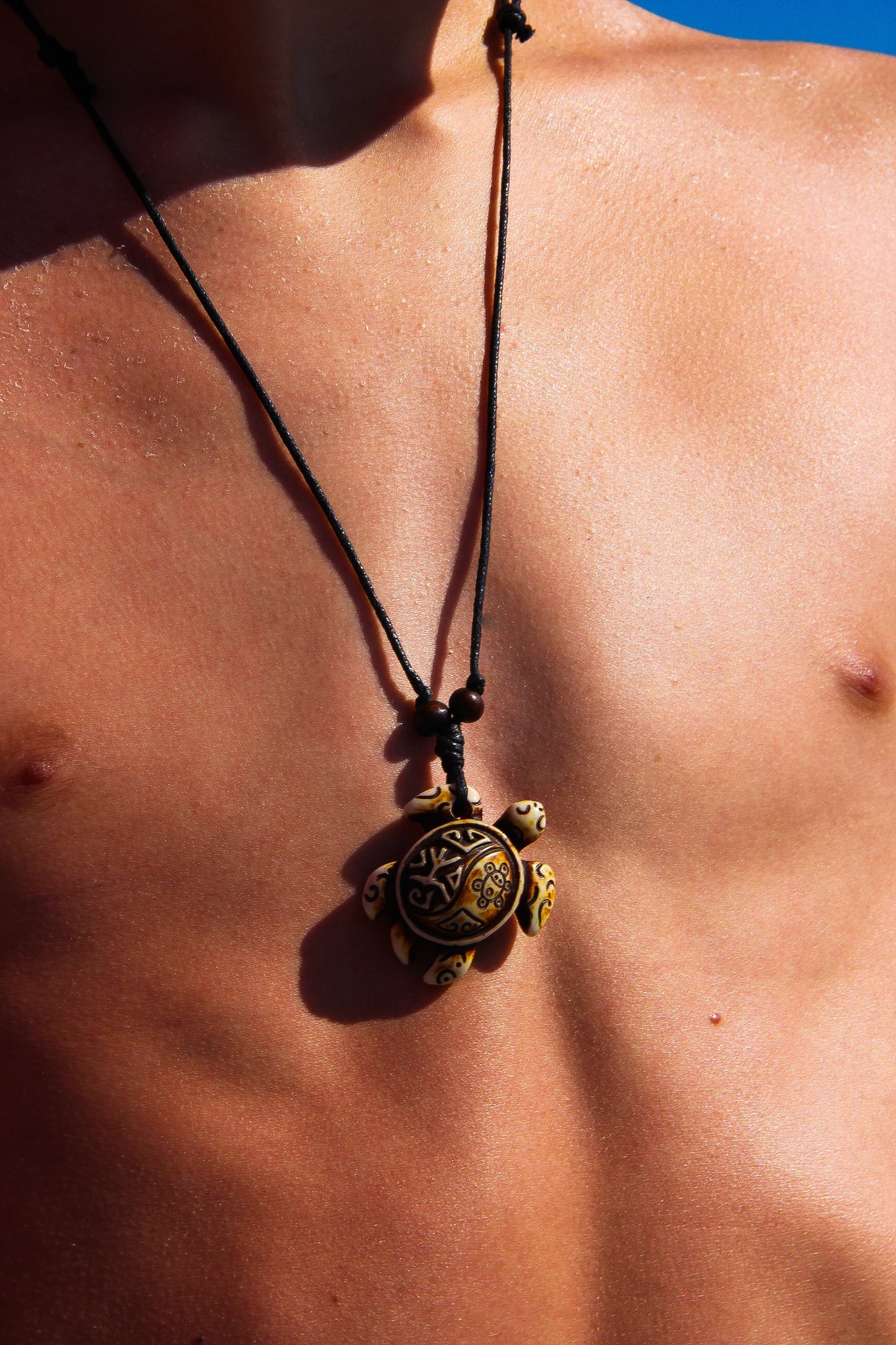 Young man wearing a sea turtle necklace of black cord with a sea turtle pendant