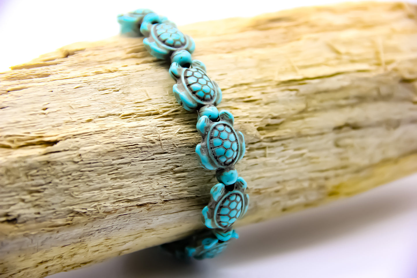 Bracelet of turquoise stone sea turtles displayed on a piece of driftwood