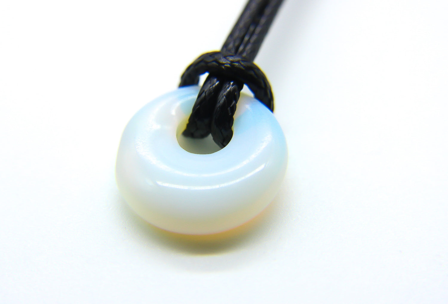 Circular white opal gemstone pendant on a black cord choker 