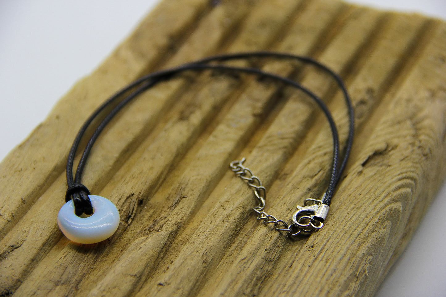 Black cord necklace with circular white opal pendant 