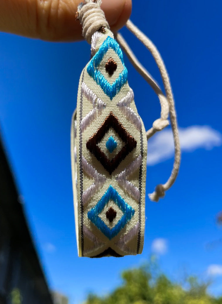 Aztec style surf bracelet held up to a blue sky